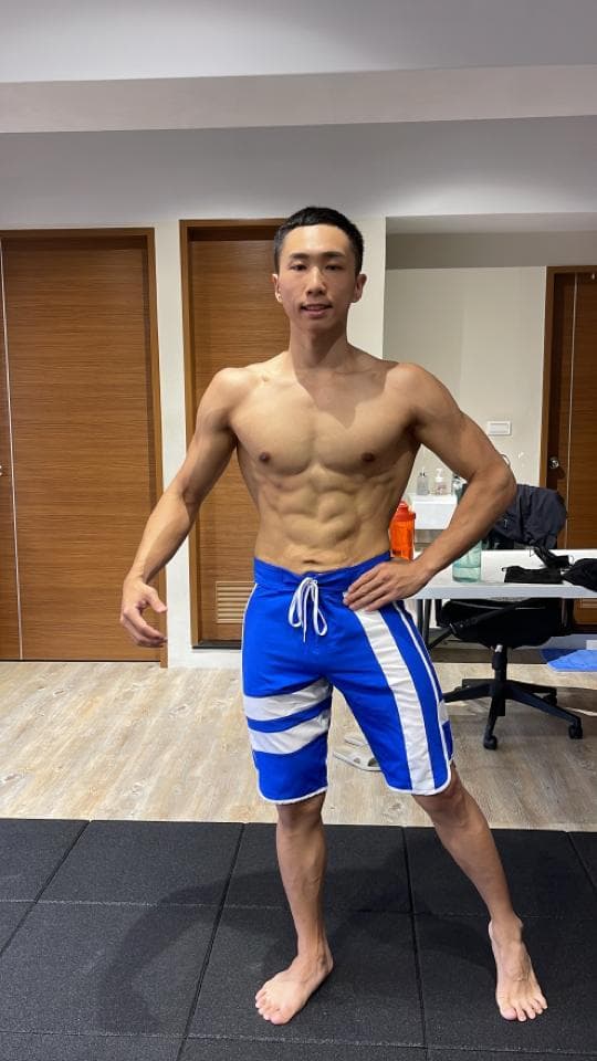 這張照片是一個年輕人穿著藍白相間的運動短褲,展現他健壯的身材。他看起來充滿自信,眼神堅定。