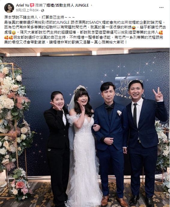 這張照片是一對新人和他們的伴娘伴郎在婚禮現場的合照。新郎穿著藍色西裝,新娘穿著白色婚紗,伴娘穿著黑色西裝,伴郎穿著深藍色西裝。他們都面帶笑容,看起來非常開心。