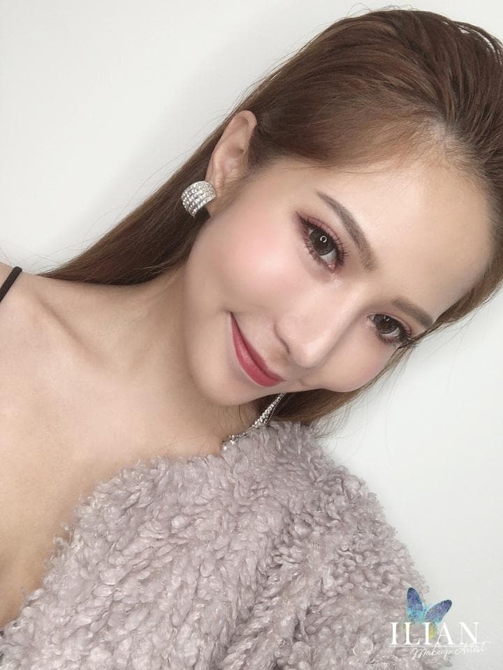 這張照片是一位年輕女子,她有著一頭長髮,穿著一件毛茸茸的衣服,臉上化著精緻的妝容,戴著閃亮的耳環,看起來很優雅美麗。