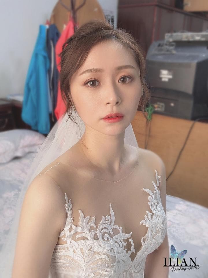 這張照片是一個美麗的新娘,她穿著一件蕾絲婚紗,頭上戴著頭紗,她的笑容十分迷人。