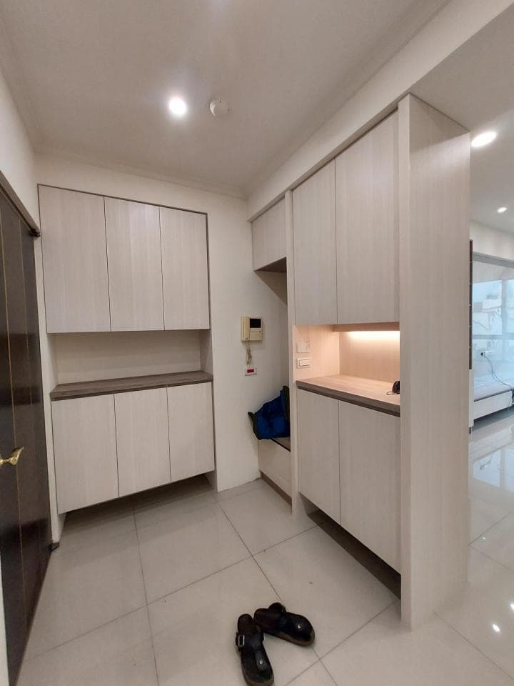 1) 照片顯示一個簡約的現代玄關,牆壁上有木質的收納櫃,地板鋪著淺色磁磚,地上放著兩雙鞋子