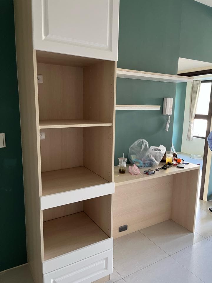 這張照片是一組白色的木質櫥櫃,上面有三個層架和一個抽屜,下方連結一個木質桌面。