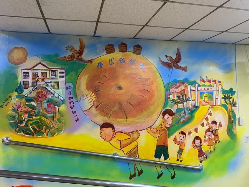 這張「牆壁」的照片是描繪一群小朋友在抬一個大餅,背景是房屋和鳥。