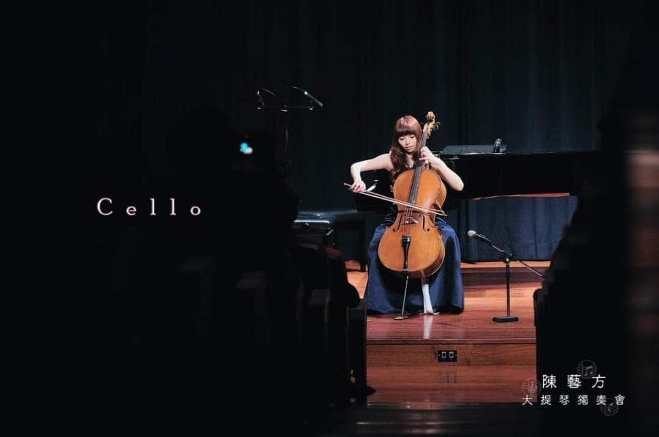 1) 照片中,一位年輕女性身穿藍色長裙,正在舞台上演奏大提琴