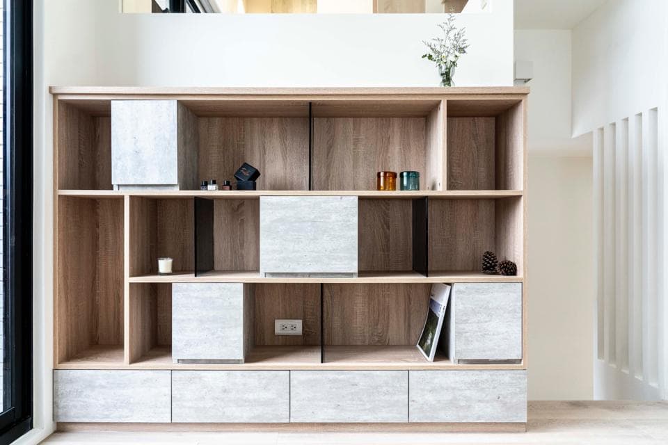 這張照片是一間現代化的室內空間,最引人注目的部分是一個大型的木質置物架,它分隔成許多格層,用於存放各種物品,設計簡潔,質感精緻。