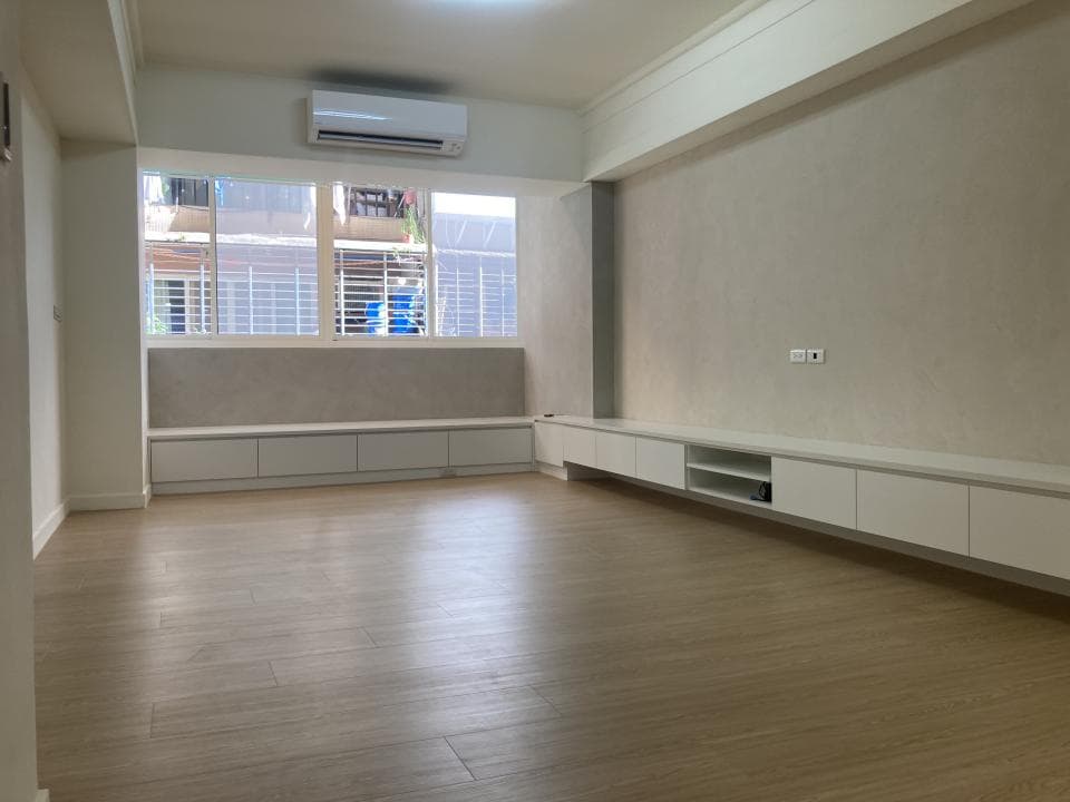 1) 照片顯示一個空房間,房間裡有木質地板,白色的牆壁,一個大的窗戶和一個電視櫃