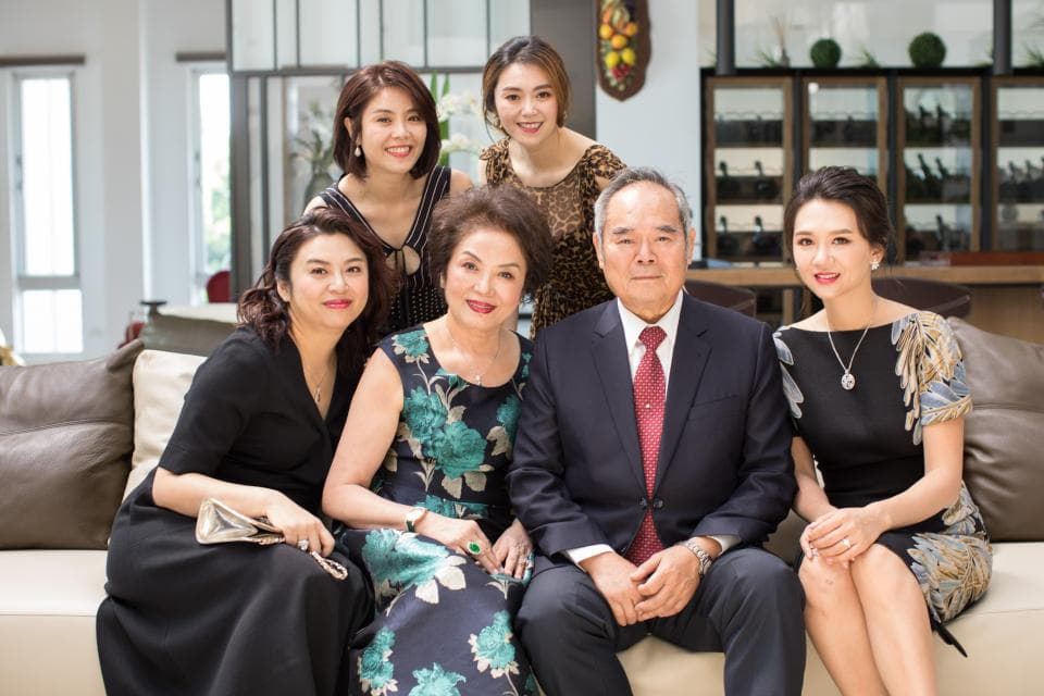 這張照片是一家人在豪華的客廳裡拍照,照片的中心是坐在中間的父親,他穿著筆挺的西裝,表情嚴肅,給人一種自信和穩重的感覺。