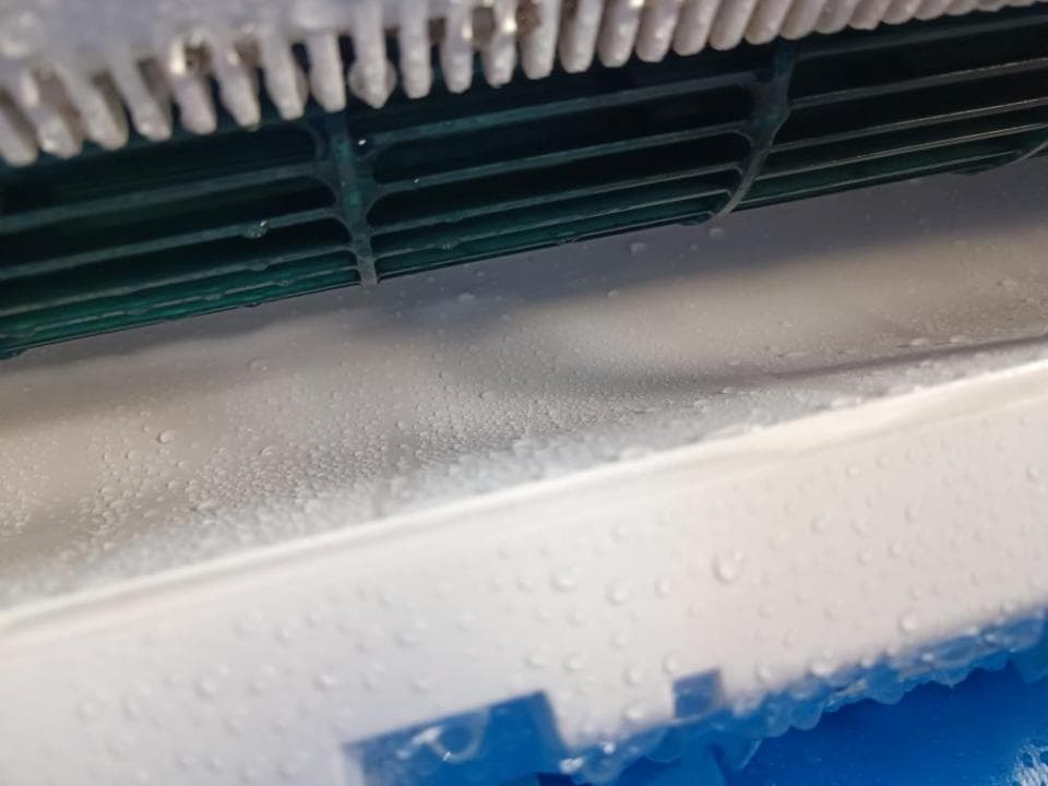 1. 照片顯示一個白色冷氣機的正面,冷氣機的冷凝水從機體上滴下來