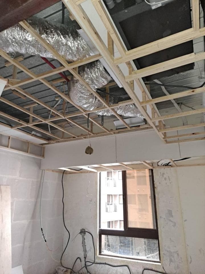 1) 照片顯示一個正在進行的室內裝修工程,天花板正在裝設木樑,部分木樑已安裝完成,可以看到裝潢用的管道