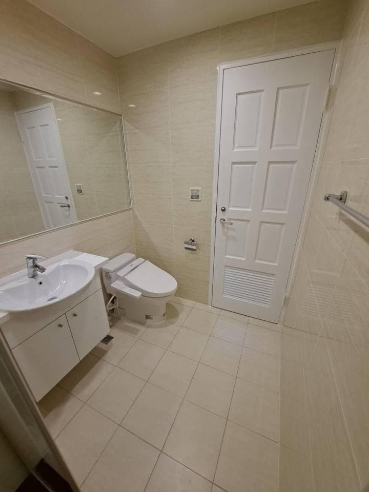 1) 照片顯示一間浴室,其中有馬桶、洗手台、鏡子、門和瓷磚地板