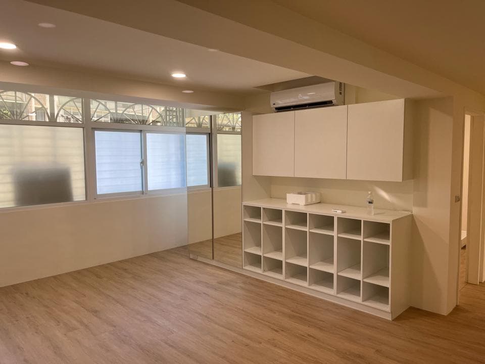 這張照片是一個明亮的房間,房間裡有一個大型的白色儲物櫃,有許多層架,很適合收納物品。