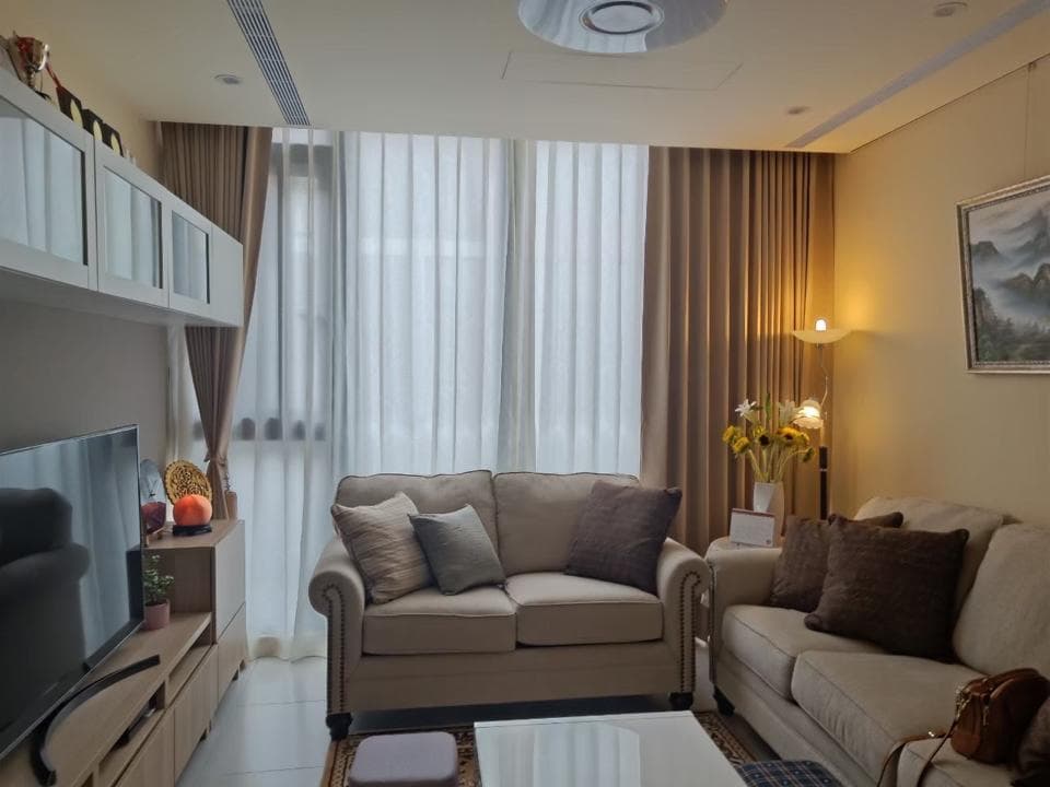 1) 照片顯示一間裝潢精緻的客廳,有著落地窗和窗簾,並有兩張沙發、電視、櫃子、燈光以及裝飾品