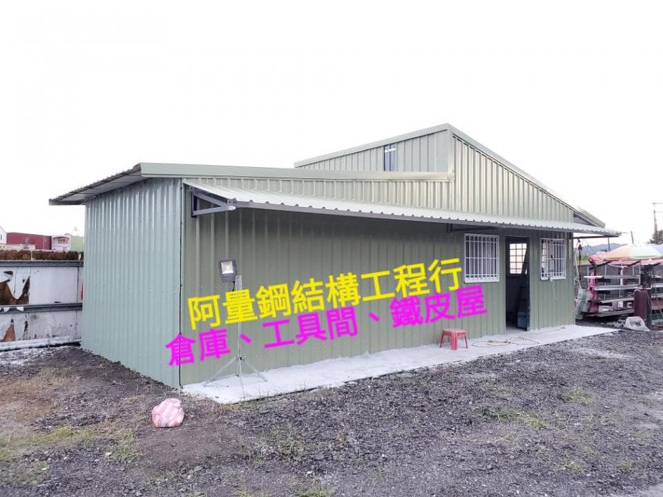 1) 照片顯示一座灰色金屬屋頂的建築物,其正面有一個入口