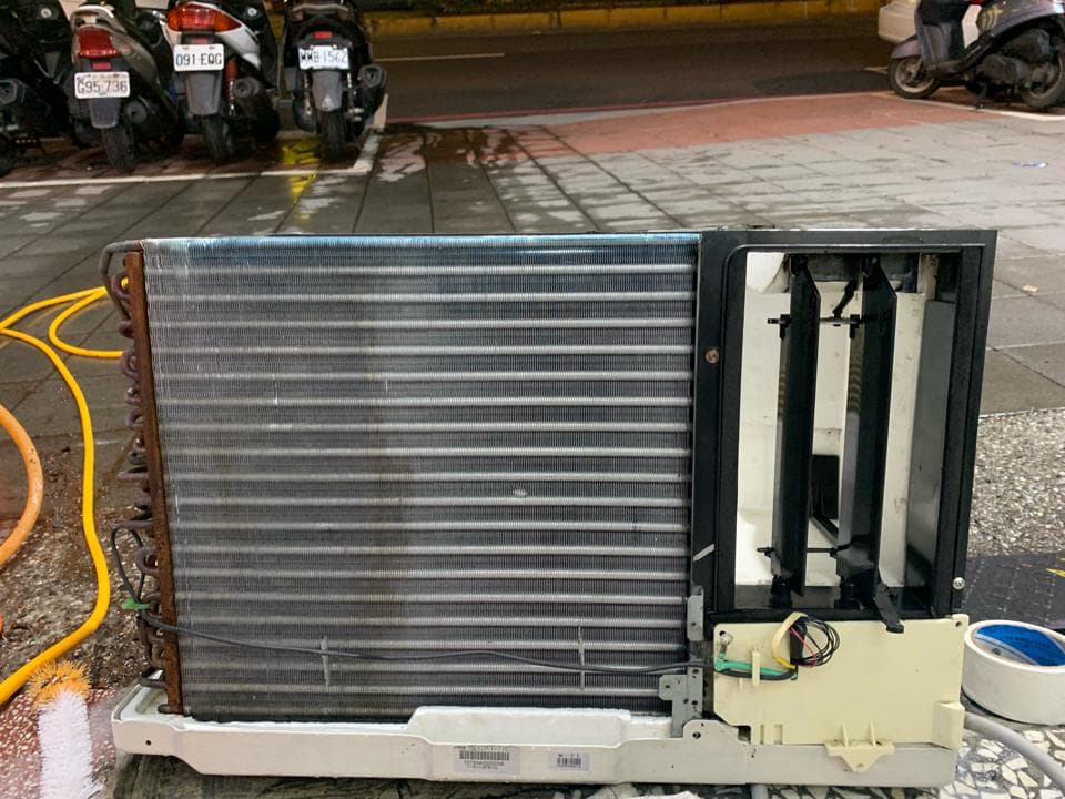 這張照片是一台室外機,它的散熱片上有許多灰塵和污垢,看起來已經很久沒有清洗了。