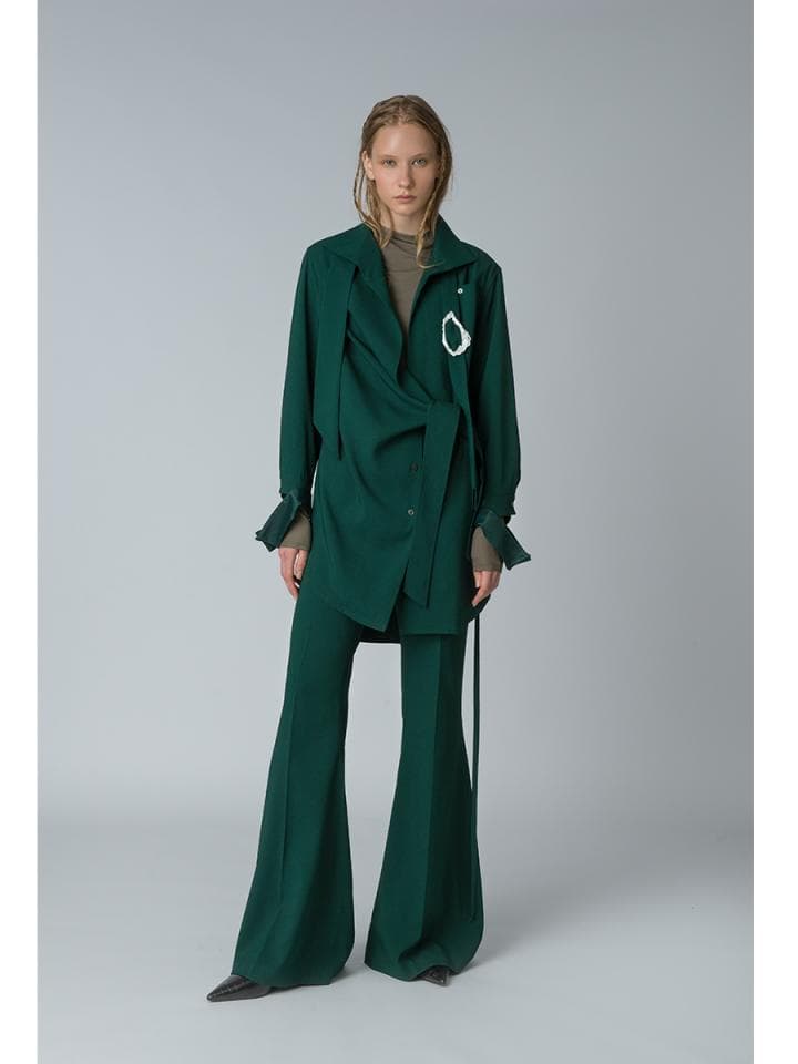這張「時尚」的照片是一個穿著深綠色外套和褲子的女性,她看起來很時髦,外套的設計獨特,褲子是喇叭褲,整體搭配很有個性。