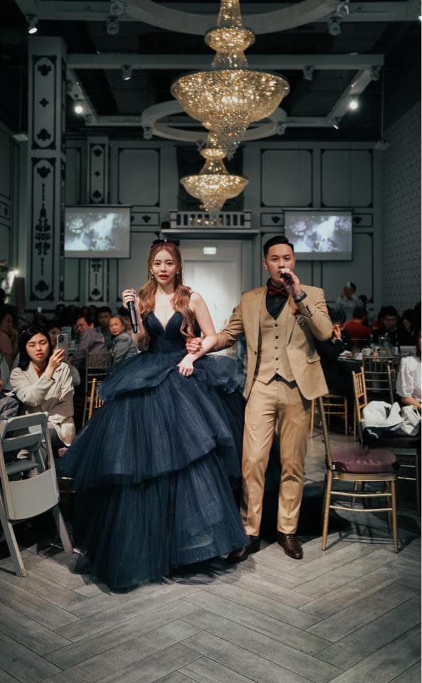 這張「婚禮」的照片是一對新人在舞臺上接受祝福,新娘穿著藍色的禮服,新郎穿著棕色的西裝。