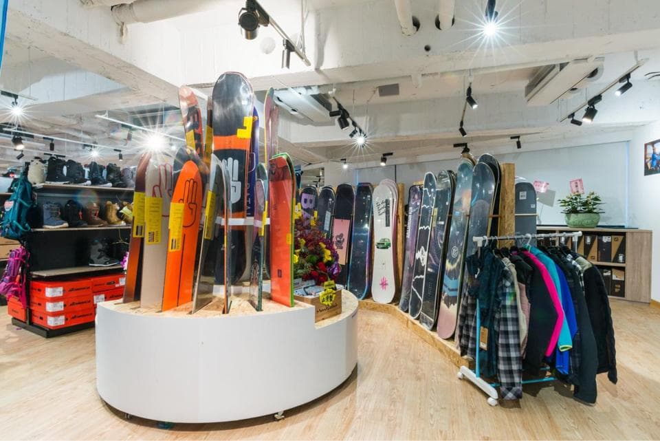 這張「滑雪板店」的照片是 一家店裡有很多不同品牌的滑雪板,也有一些滑雪服裝。
