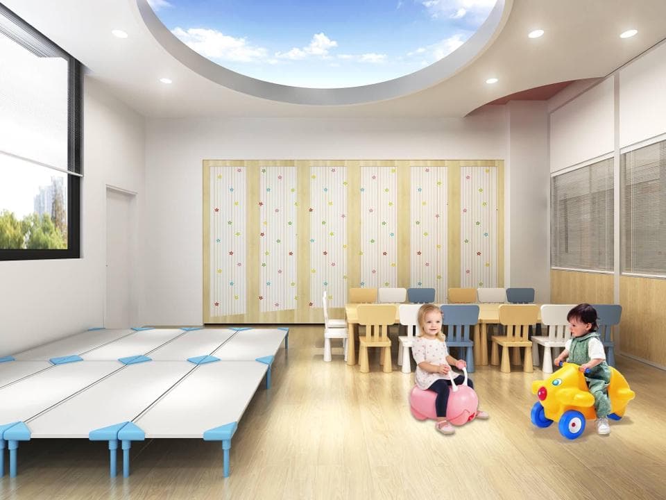 這張「兒童遊樂場」的照片是一間寬敞明亮的房間,裡面有兩個小孩,一個坐在粉紅色的玩具上,另一個騎著黃色的玩具車,房間中間有許多藍色的軟墊。