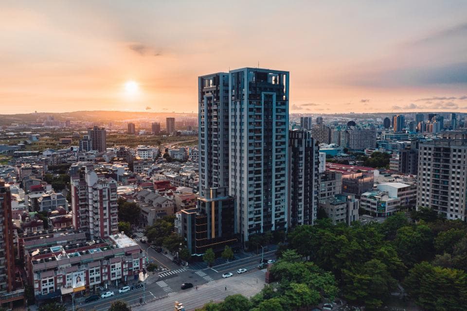 這張「城市景觀」的照片是黃昏時分,一座高聳的摩天大樓矗立在夕陽下,周圍是其他建築物和樹木,展現了城市繁華的景象。