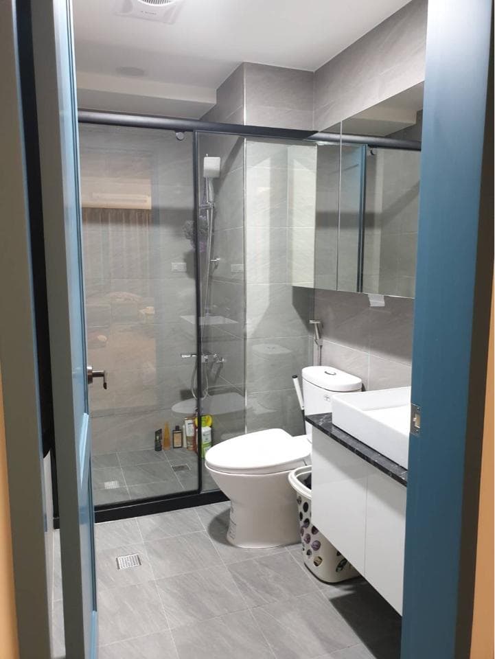 1) 照片顯示一個現代浴室,配有玻璃淋浴間、馬桶、洗手台、鏡子以及白色櫥櫃