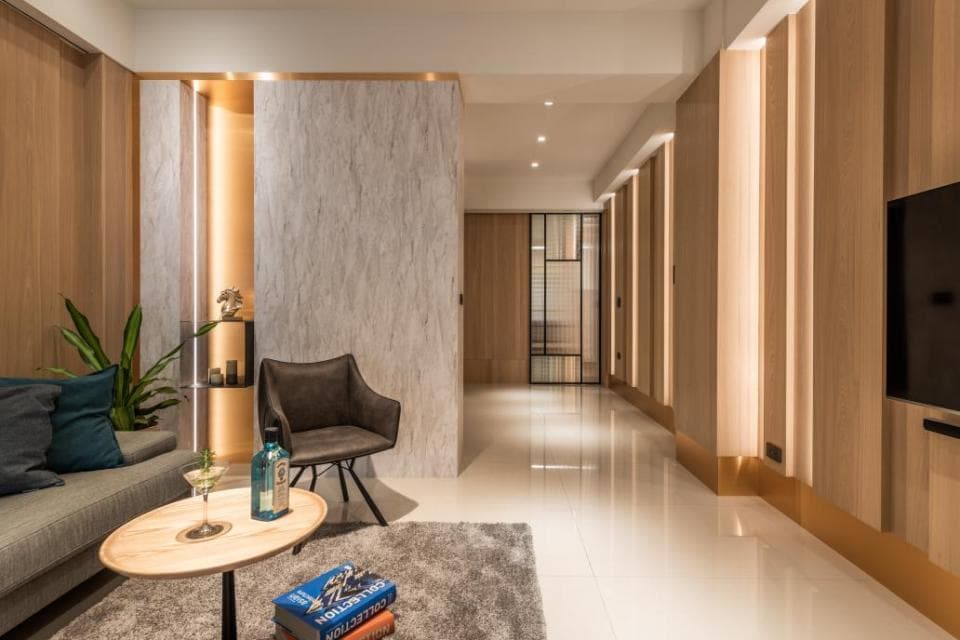 這張「現代化客廳」的照片是一間裝潢精緻的空間,有著木質地板、牆壁和天花板,以及一個灰色皮革沙發和一個金屬茶几。房間裡還有許多植物,營造出自然舒適的氛圍。