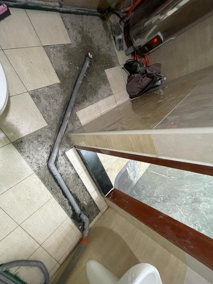 1) 照片中顯示一個浴室正在進行翻修,有一個白色瓷磚地板,上面有灰塵和泥土