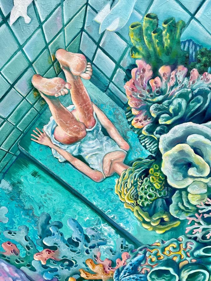 這張照片是一個年輕女子躺在一個裝飾著海洋生物的瓷磚浴室地板上。她穿著一件白色連衣裙,頭髮呈波浪狀。地板上佈滿了色彩鮮豔的海星、珊瑚和魚類。