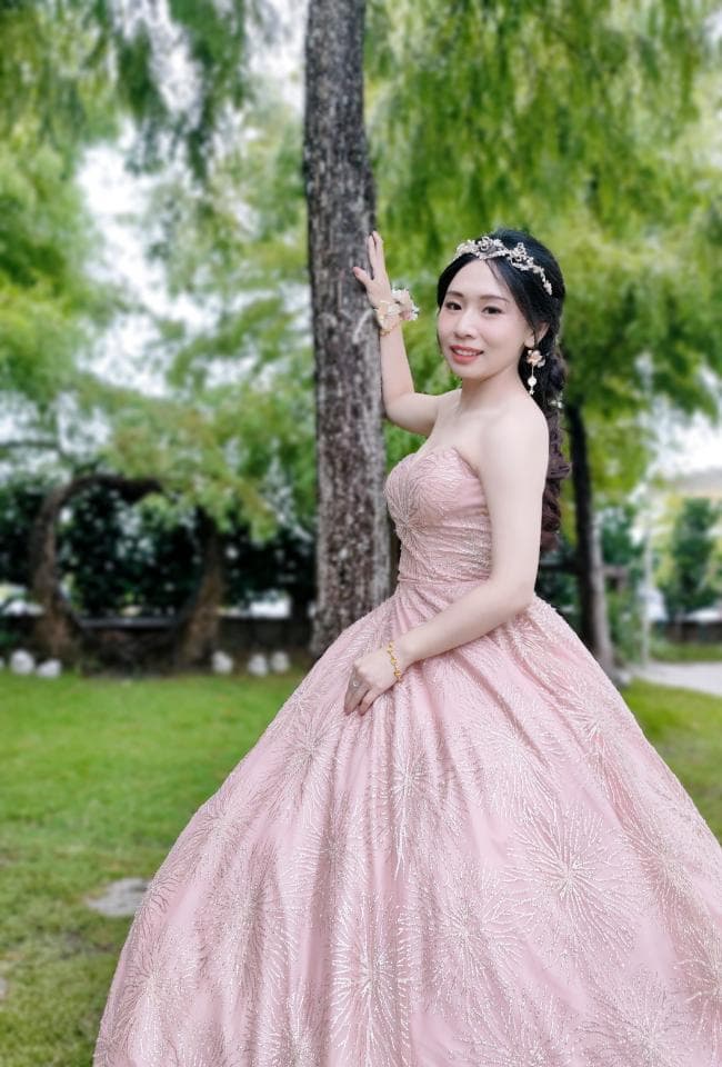 這張「婚紗照」的照片是一名穿著粉紅色蓬裙婚紗的女子,她站在樹旁,露出甜美的笑容。
