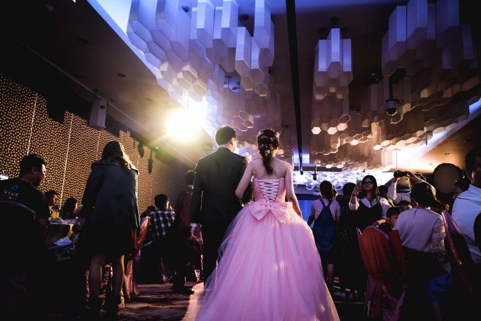 這張「婚禮」的照片是新郎新娘在婚禮現場,新娘穿著粉紅色的婚紗,新郎則穿著西裝。周圍是婚禮賓客,他們正在觀看婚禮。