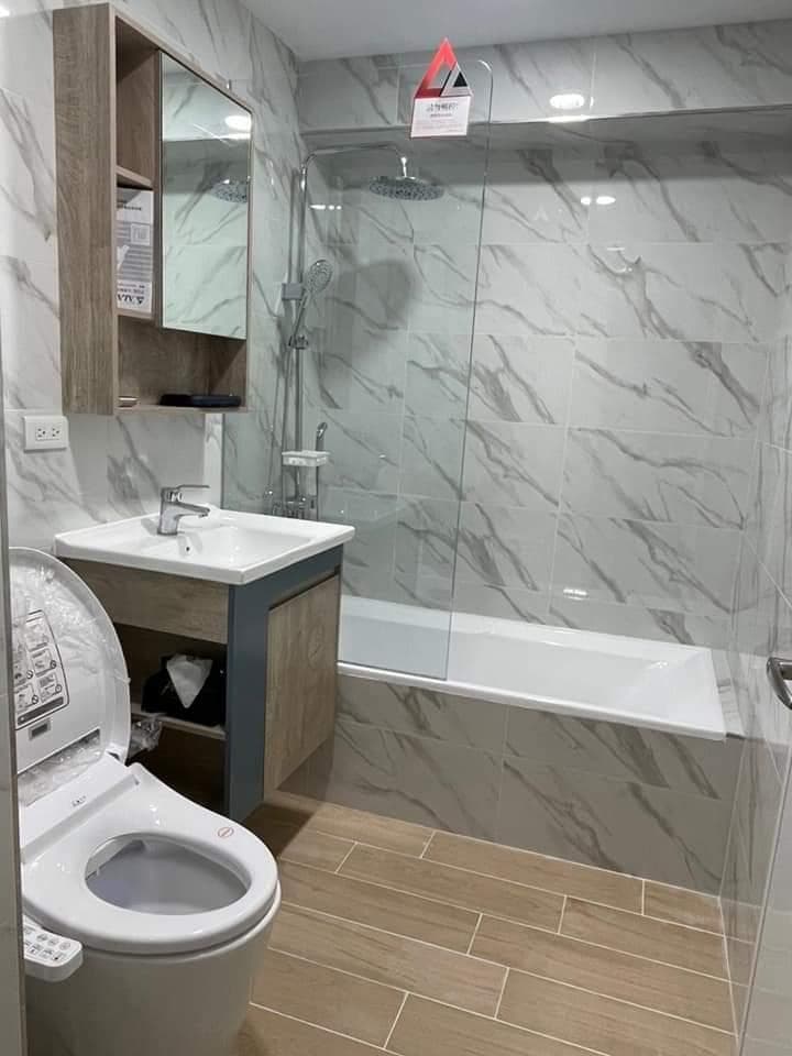 這張照片是一個現代化的浴室,最重要的是智能馬桶。它有白色陶瓷外殼和木質座墊,並且配備有許多功能,包括自動沖水和溫水洗淨。