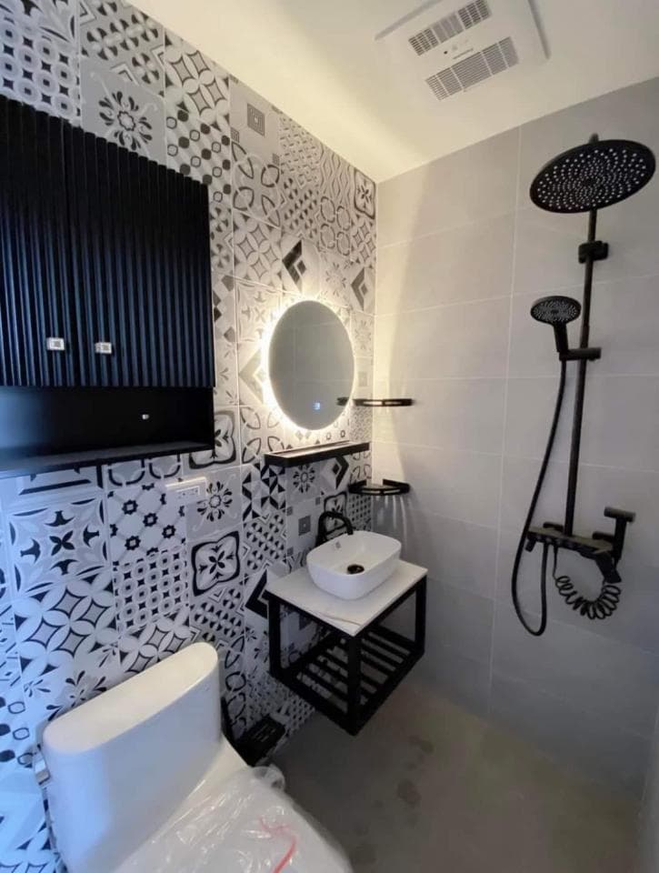 1) 照片顯示一個現代的浴室,牆壁上鋪著黑白相間的磁磚,牆上裝飾著黑色金屬架,上面放著一個圓形的鏡子