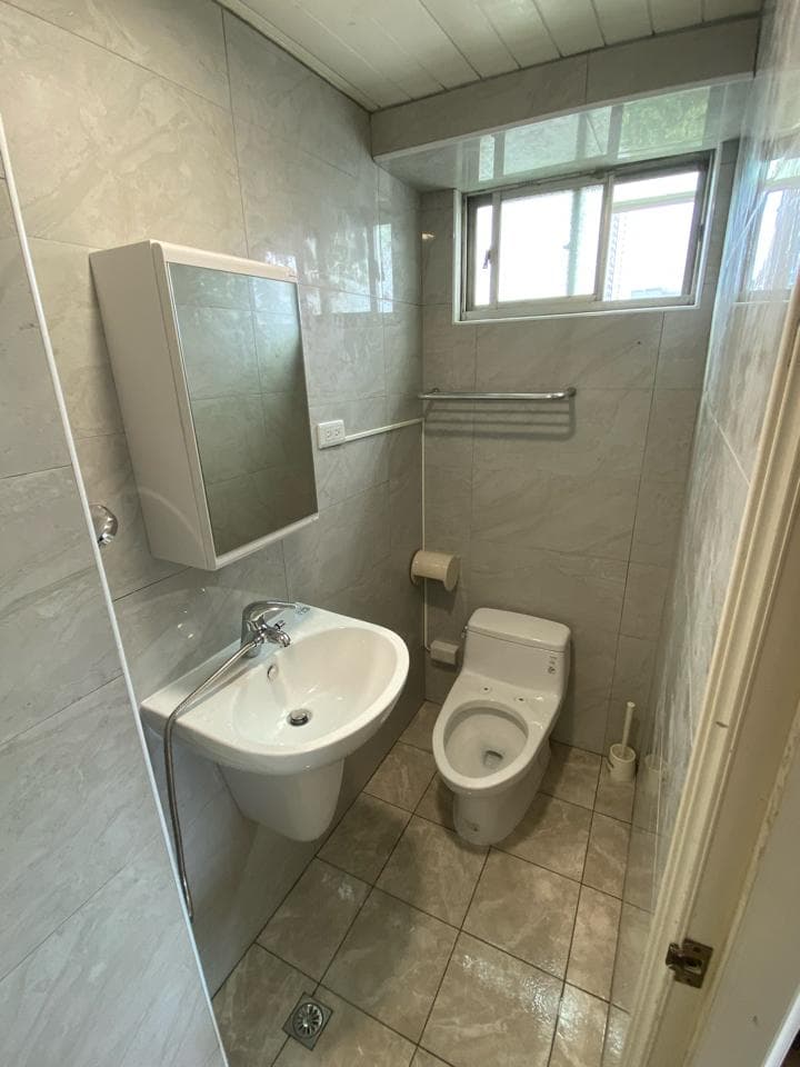 1) 照片顯示一個浴室,浴室裡有馬桶、洗手台、鏡子、毛巾架,牆壁和地板都鋪設了瓷磚