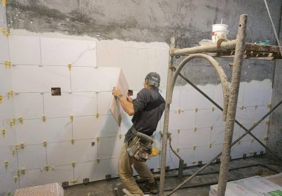 1) 照片顯示一位男子正在用梯子安裝牆磚