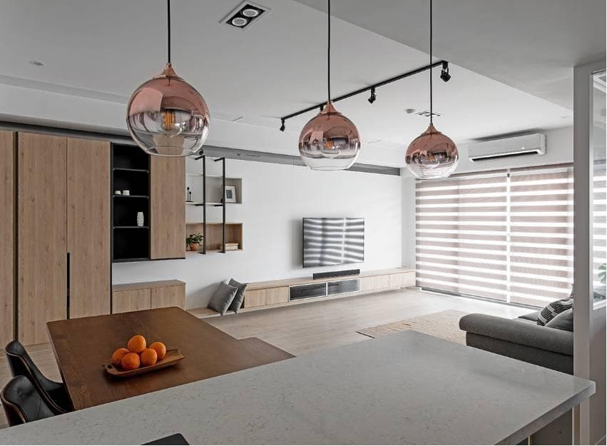 這張照片是一個現代化的客廳,其中最醒目的部分是三個懸掛的銅色燈泡,它們的光線照亮了整個空間,營造出溫馨舒適的氛圍。