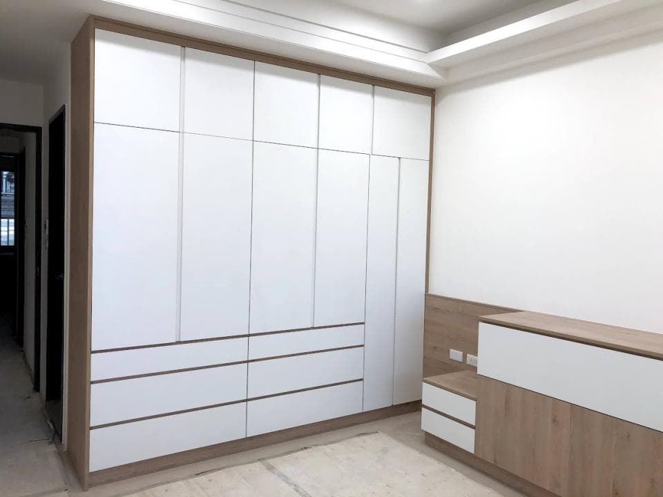 這張照片是一個現代化的臥室,其中最重要的是一個大型的白色衣櫃,它佔據了牆壁的大部分空間,看起來既實用又美觀。