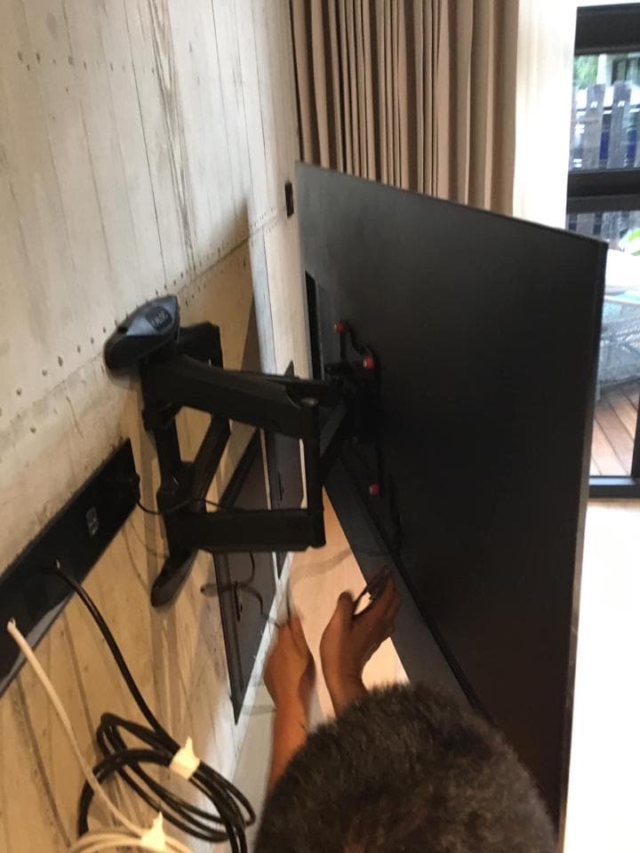 1) 照片顯示一個人正在安裝一臺電視機,電視機已安裝在牆上,但仍有人正在安裝