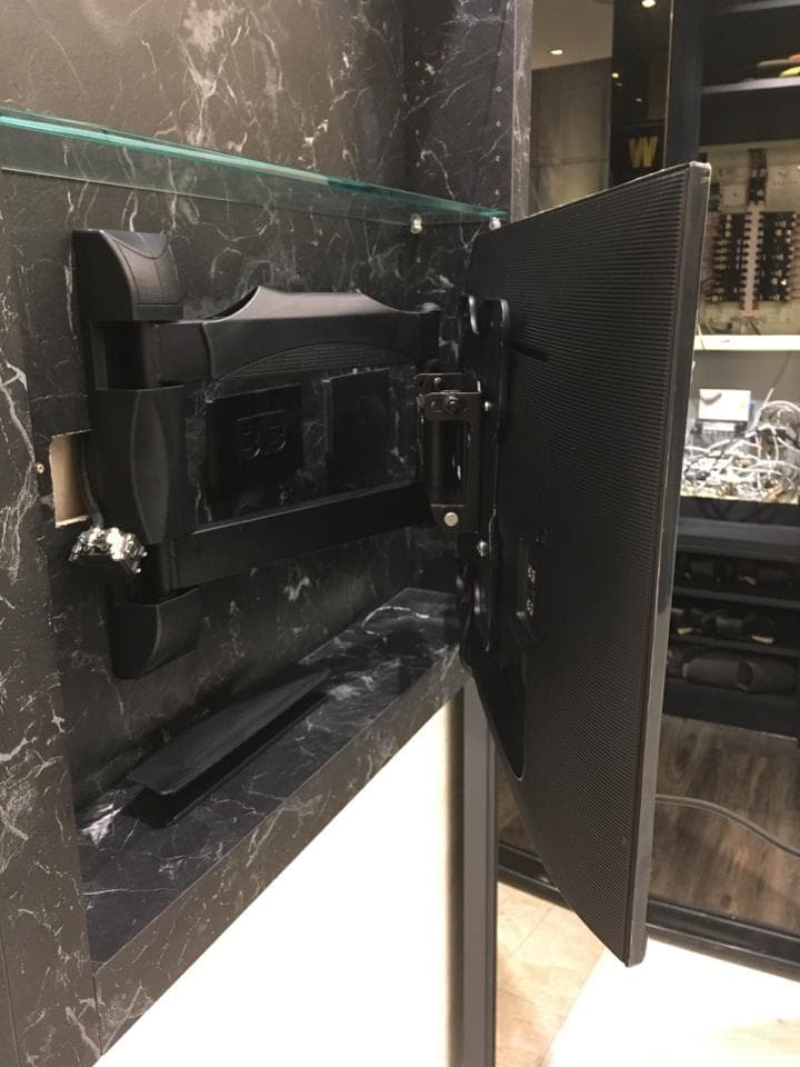 這張照片是一台安裝在牆上的電視,電視機身是黑色,而且正在旋轉。