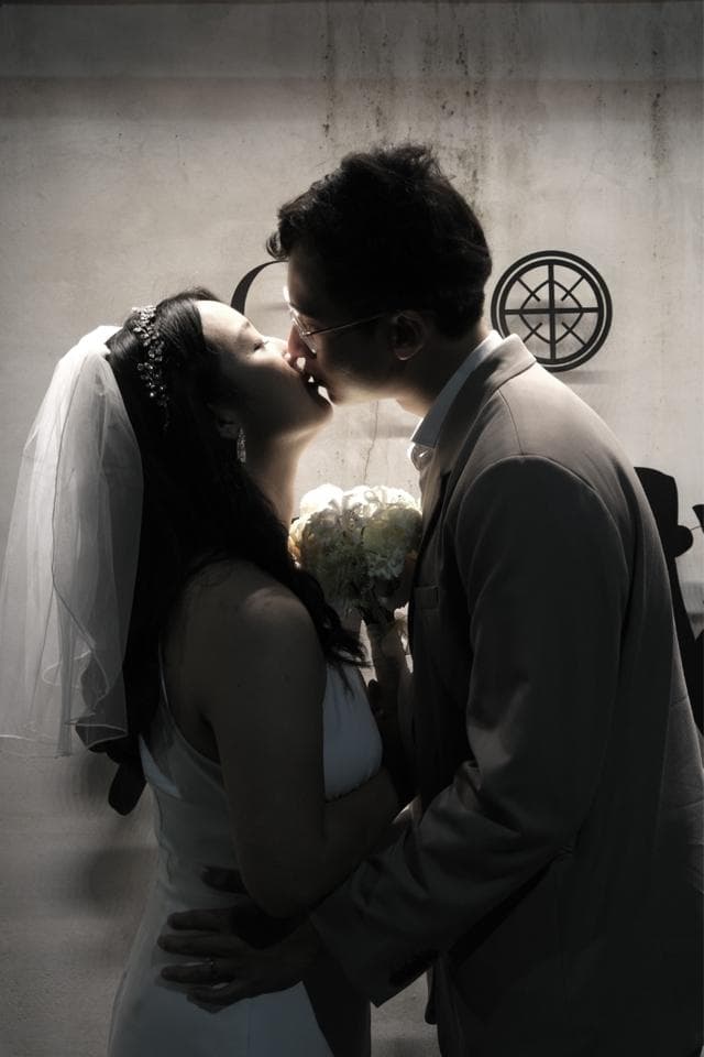 這張照片是一對情侶正在接吻。他們穿著婚紗和西裝,並手持一束鮮花。他們深情地擁抱,看起來非常幸福。