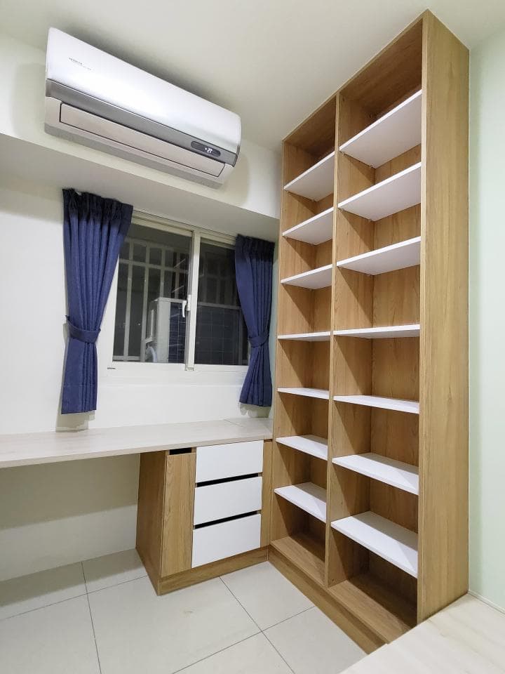 這張照片是一個房間裡面的角落,有一個大型的木製書架,上面有許多層架,可以放很多東西。书架旁边有一个白色的桌子,桌子上有一个白色的抽屉,非常简洁漂亮。