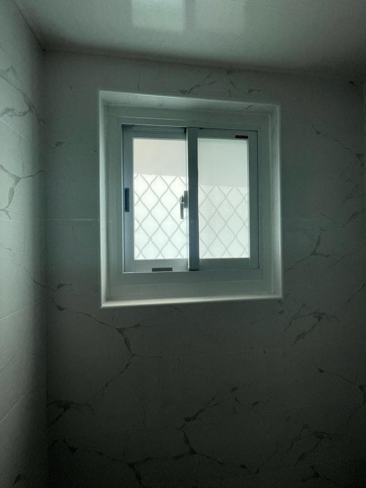 1) 照片顯示一間浴室中,帶有白色瓷磚牆壁和一個帶有窗戶的白色框架