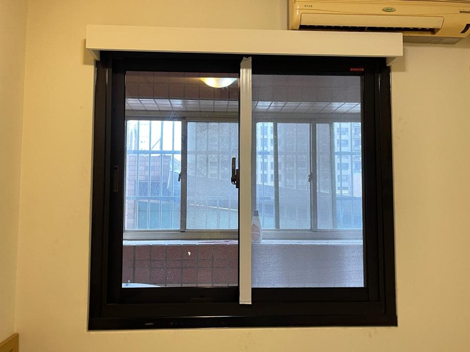 1. 照片顯示一個裝有黑色窗框和白色窗簾的窗户,窗户分為兩部分,一部分是窗戶,另一部分是紗窗,透過窗户,可以看見外面的建築物