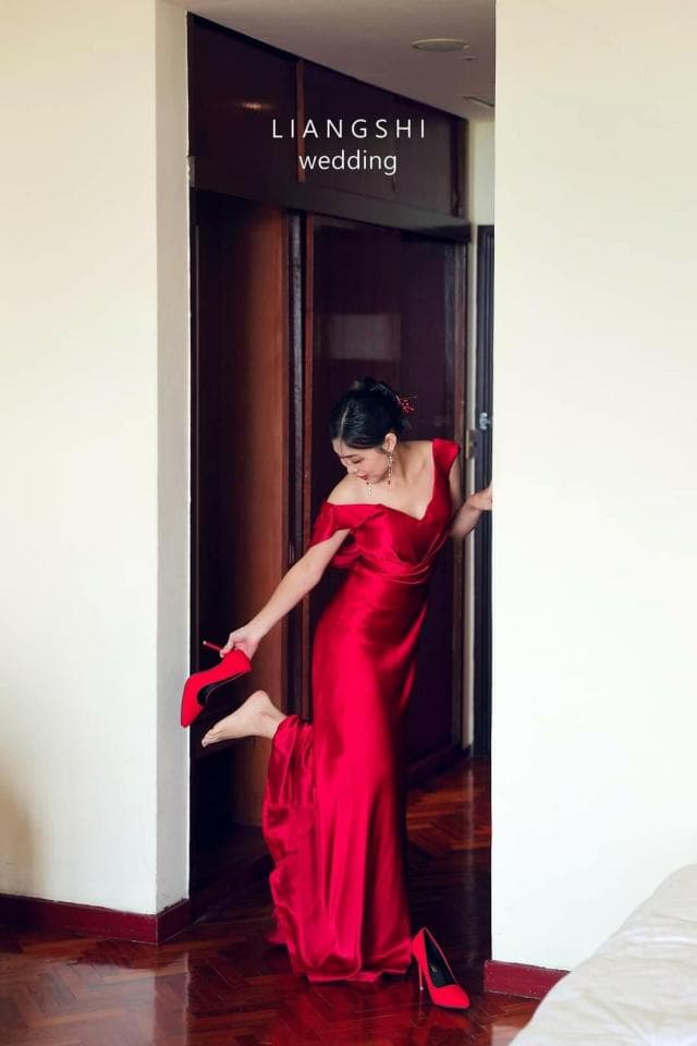 這張照片是一個穿著紅色禮服的女人,她正要穿上高跟鞋。