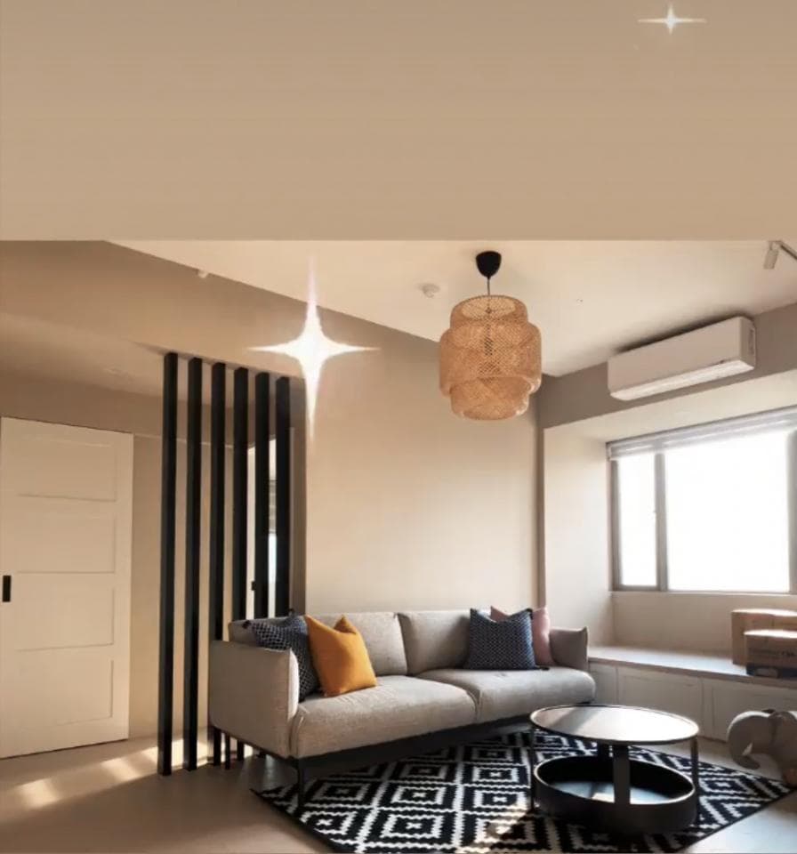 這張「客廳」的照片是,一張灰色沙發,配上黑色和白色的地毯,以及一盞竹編燈。