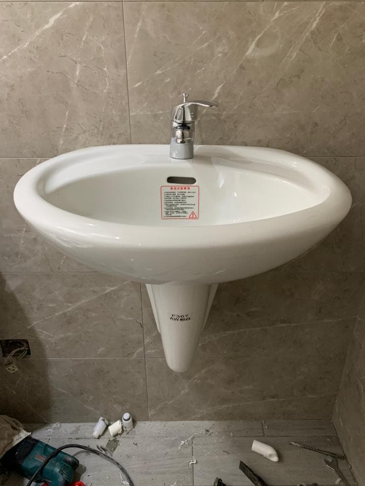 1) 照片顯示一個白色的牆壁掛式水槽,水槽上有一個銀色的水龍頭,水槽安裝在瓷磚牆壁上