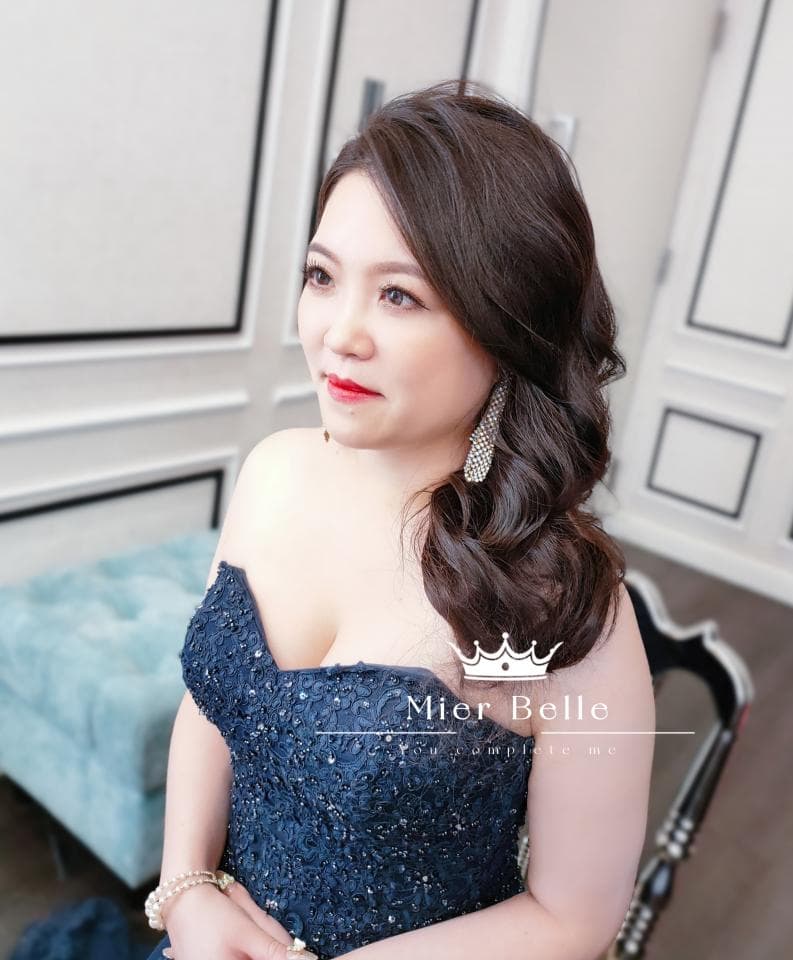 這張照片是一位穿著深藍色蕾絲禮服的女性,她的妝容精緻,髮型優雅,整體造型高貴大方。