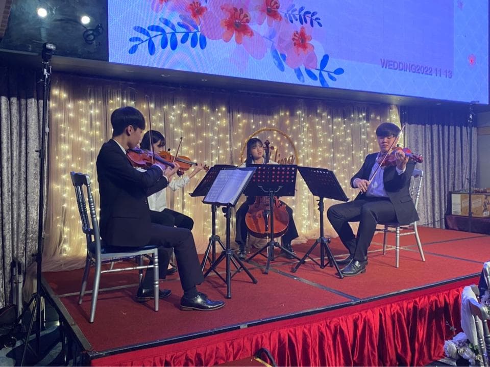 這張婚禮現場的照片是,一個弦樂四重奏正在表演,他們在舞臺上演奏小提琴和中提琴。