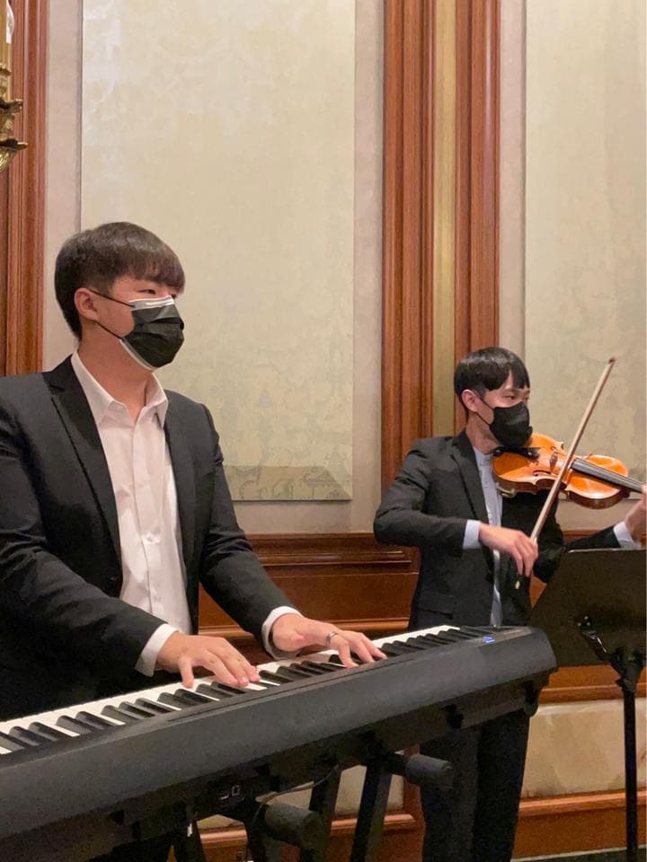 這張照片是一個穿著西裝的男人在彈奏電子琴。