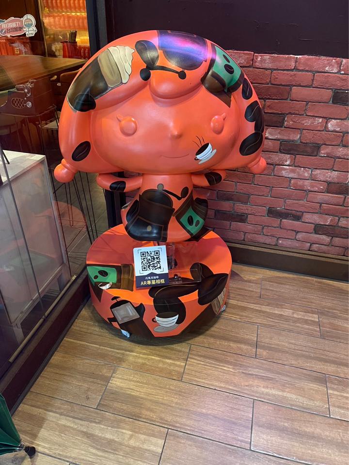 這張「可愛卡通人物」的照片是一個紅色的卡通人物,坐在一個帶有QR碼的椅子上。