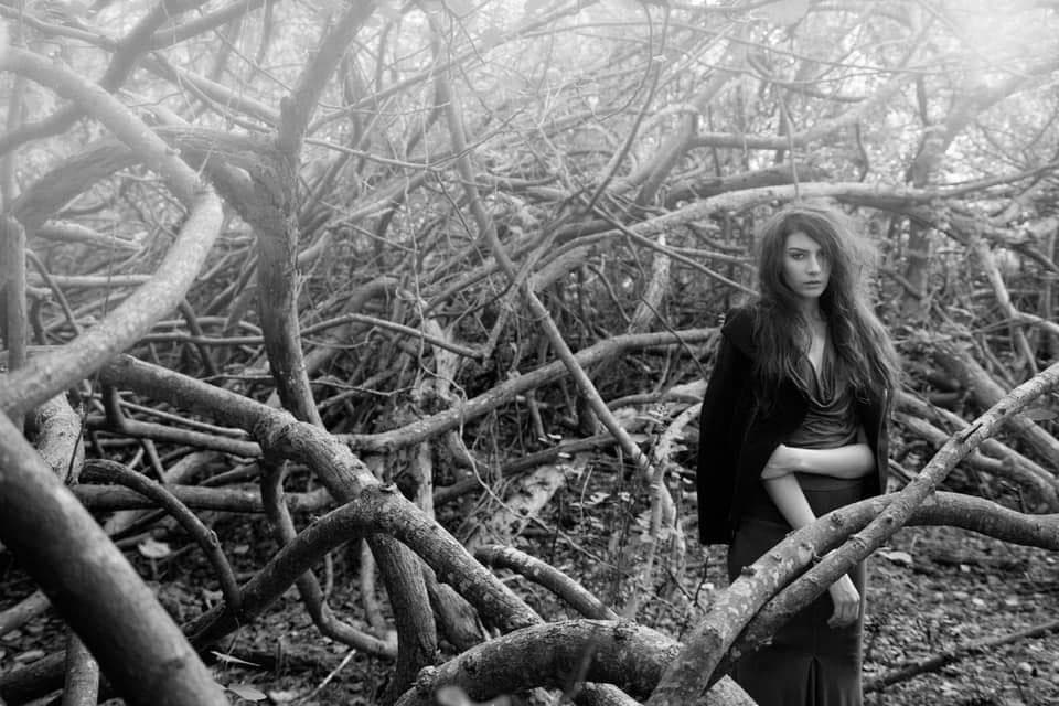 這張「樹林」的照片是一個年輕女子站在樹枝叢生的樹林中。