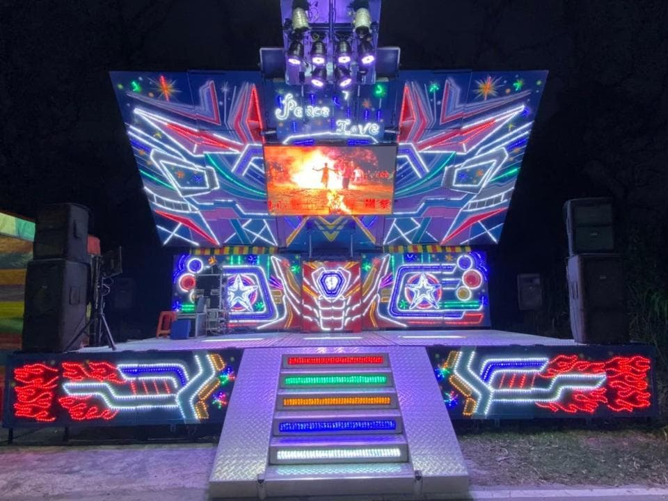 1) 這是一張照片,顯示一個用於戶外活動的舞台,裝飾著鮮豔的霓虹燈